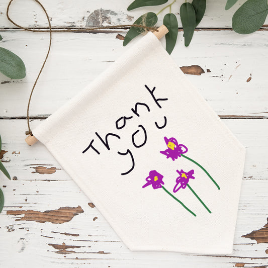 White napkin with 'Thank You' and purple flowers on a rustic wooden surface with green leaves. | Little Heirloom