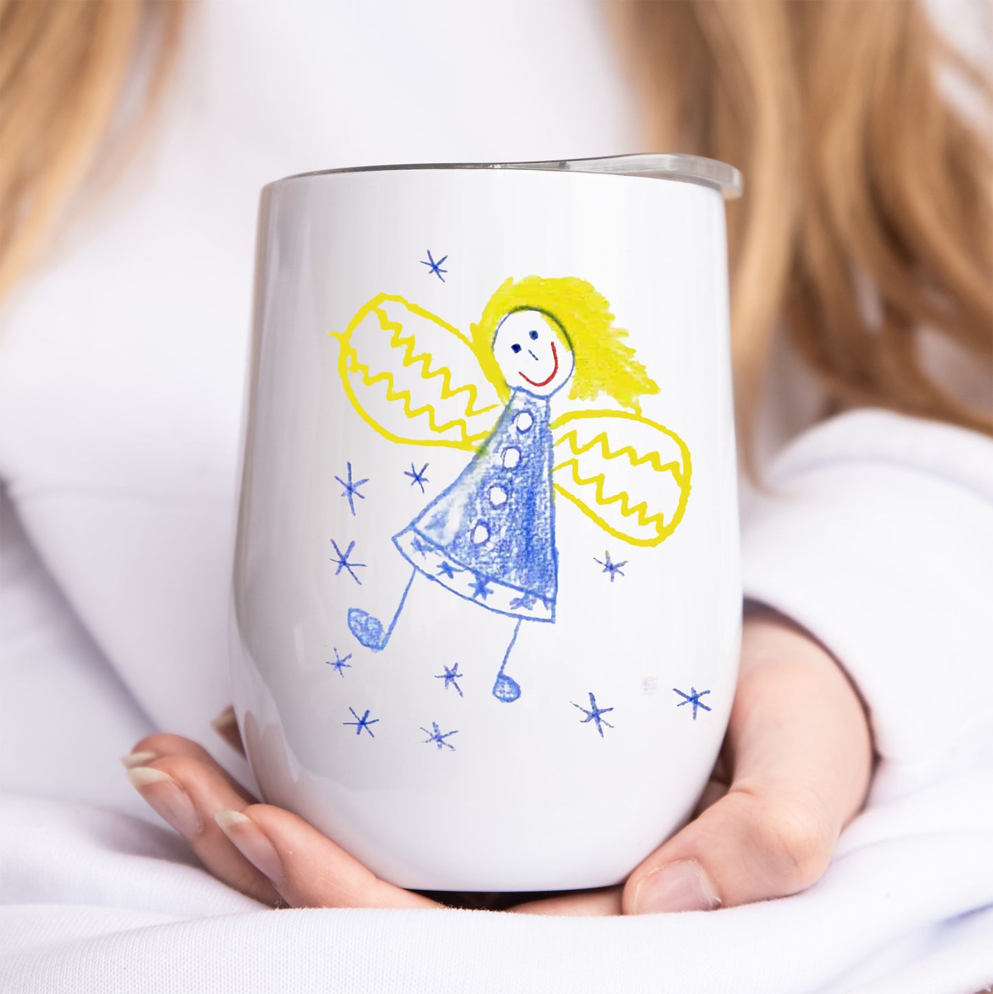 Person holding a white tumbler with a colorful drawing of an angel on it. | Little Heirloom