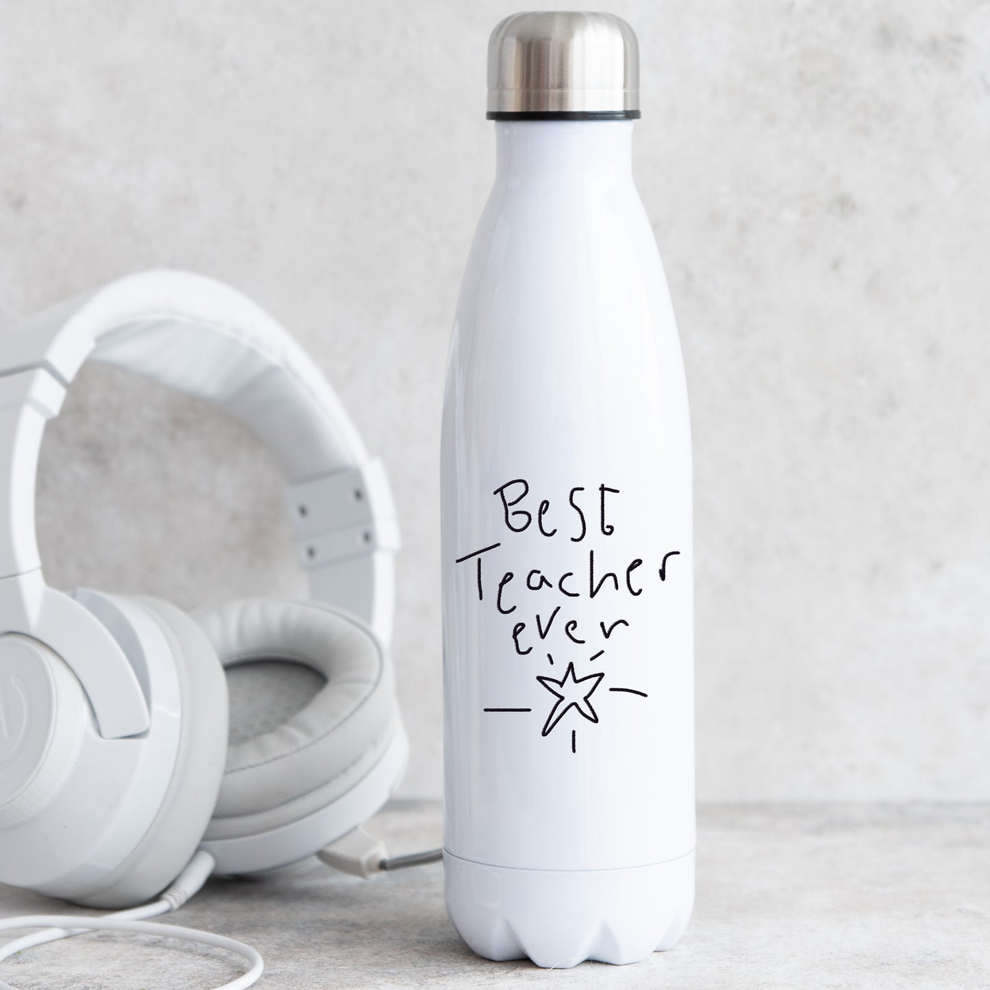 White insulated bottle with 'Best Teacher Ever' text next to white headphones on a light gray background | Little Heirloom