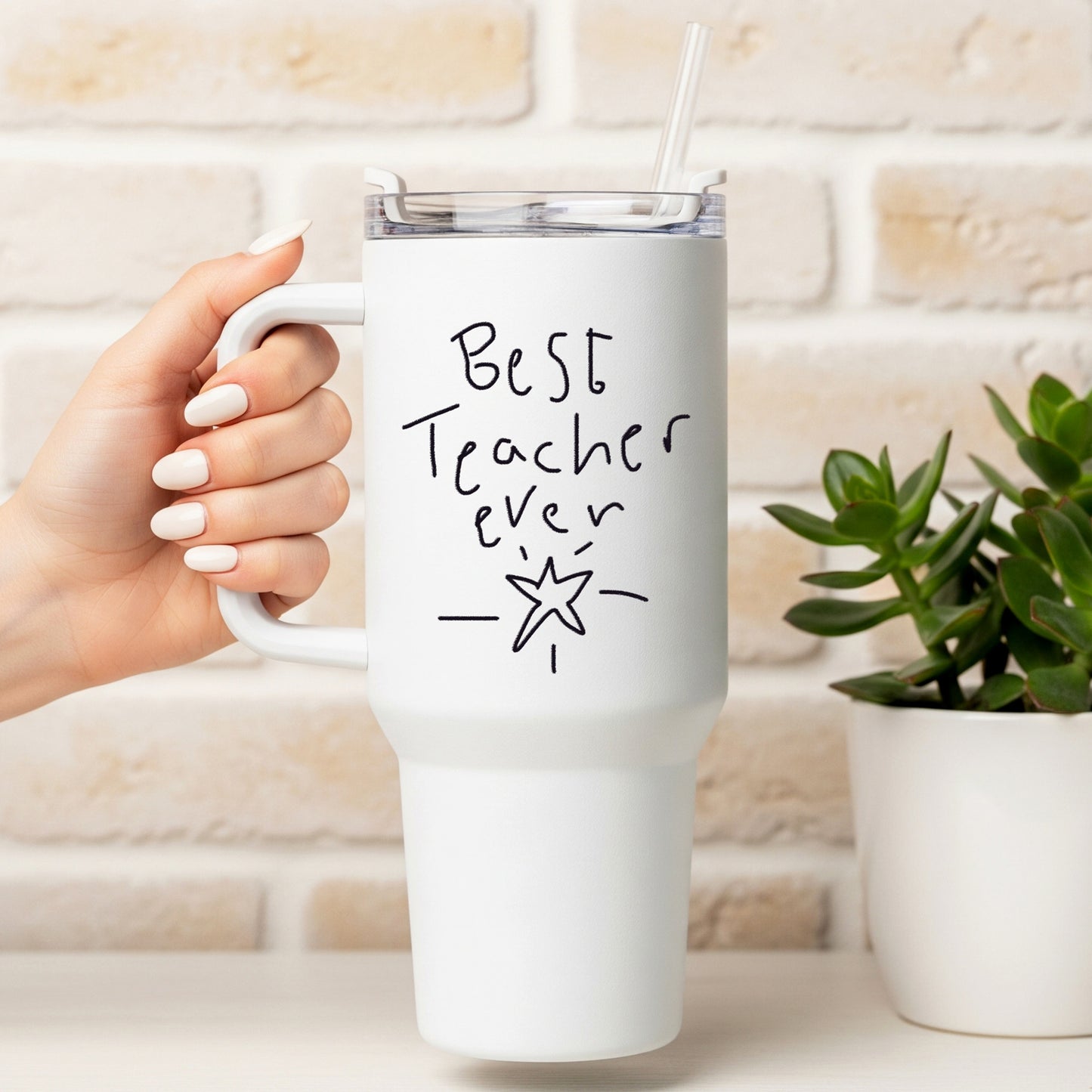White mug with 'Best Teacher Ever' text held by a hand, against a light brick wall background. | Little Heirloom