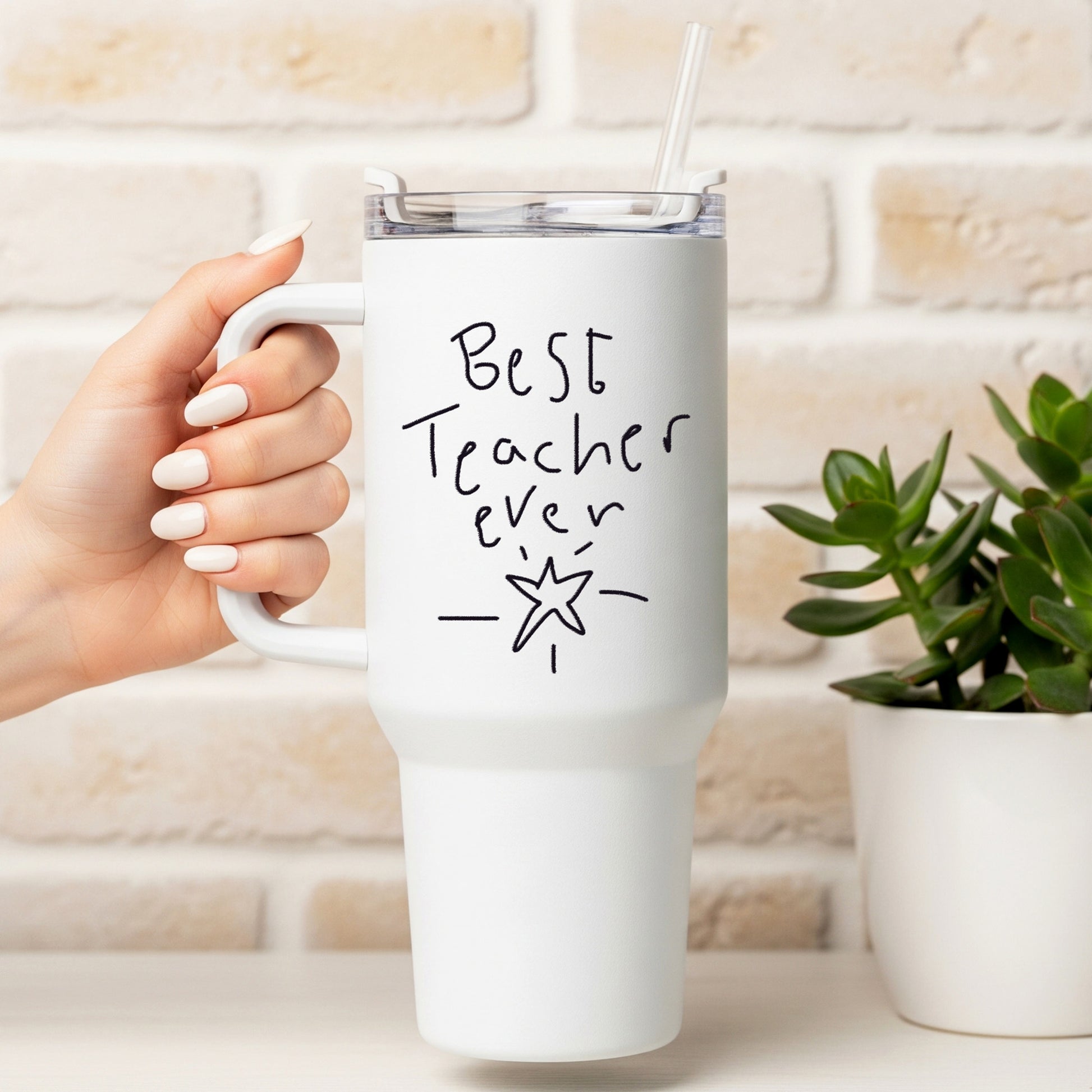White mug with 'Best Teacher Ever' text held by a hand, against a light brick wall background. | Little Heirloom