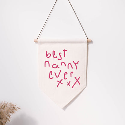 Canvas banner with 'best nanny ever' text on a white wall | Little Heirloom