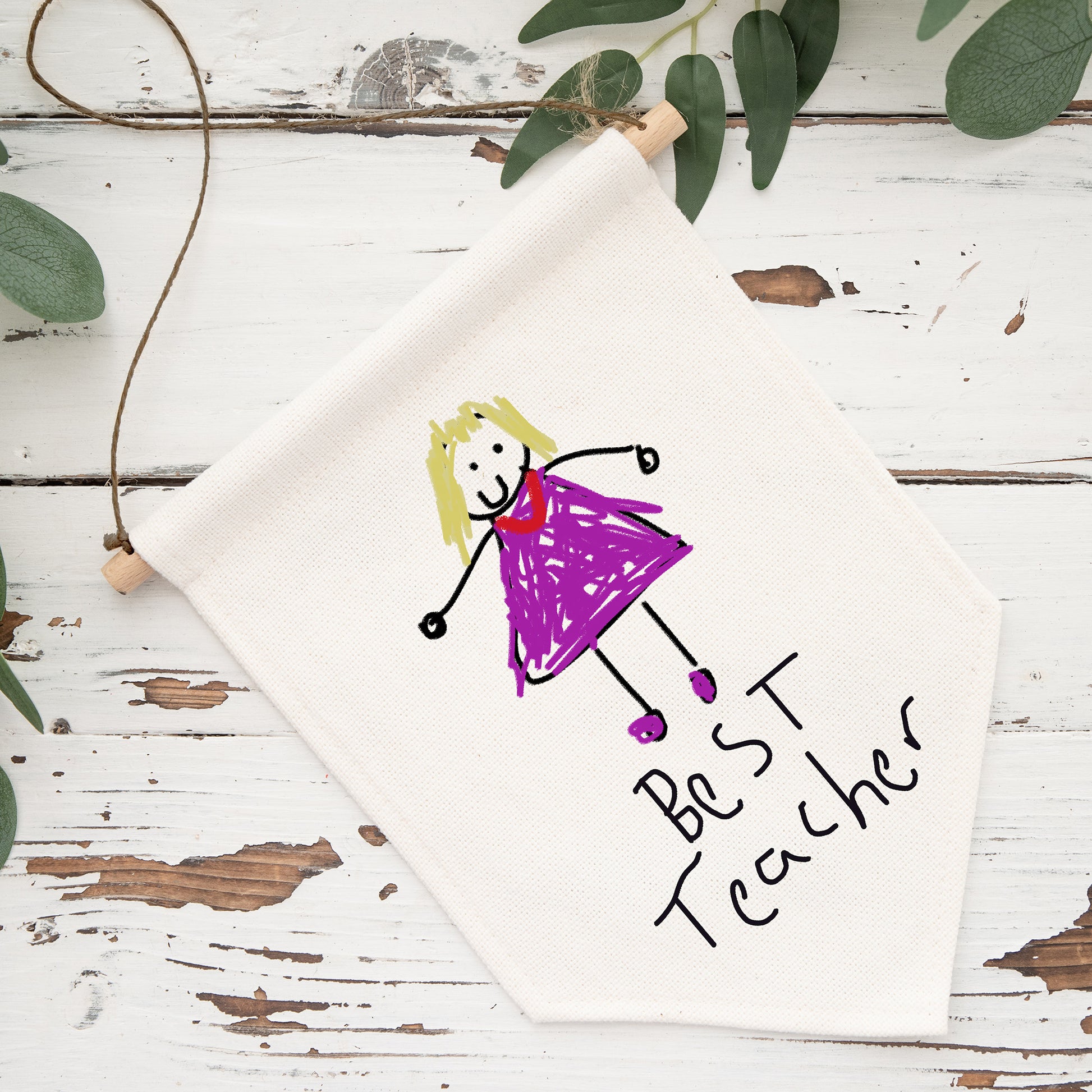 Canvas with a child's drawing of a girl in a purple dress and 'Best Teacher' text on a wooden surface with greenery. | Little Heirloom