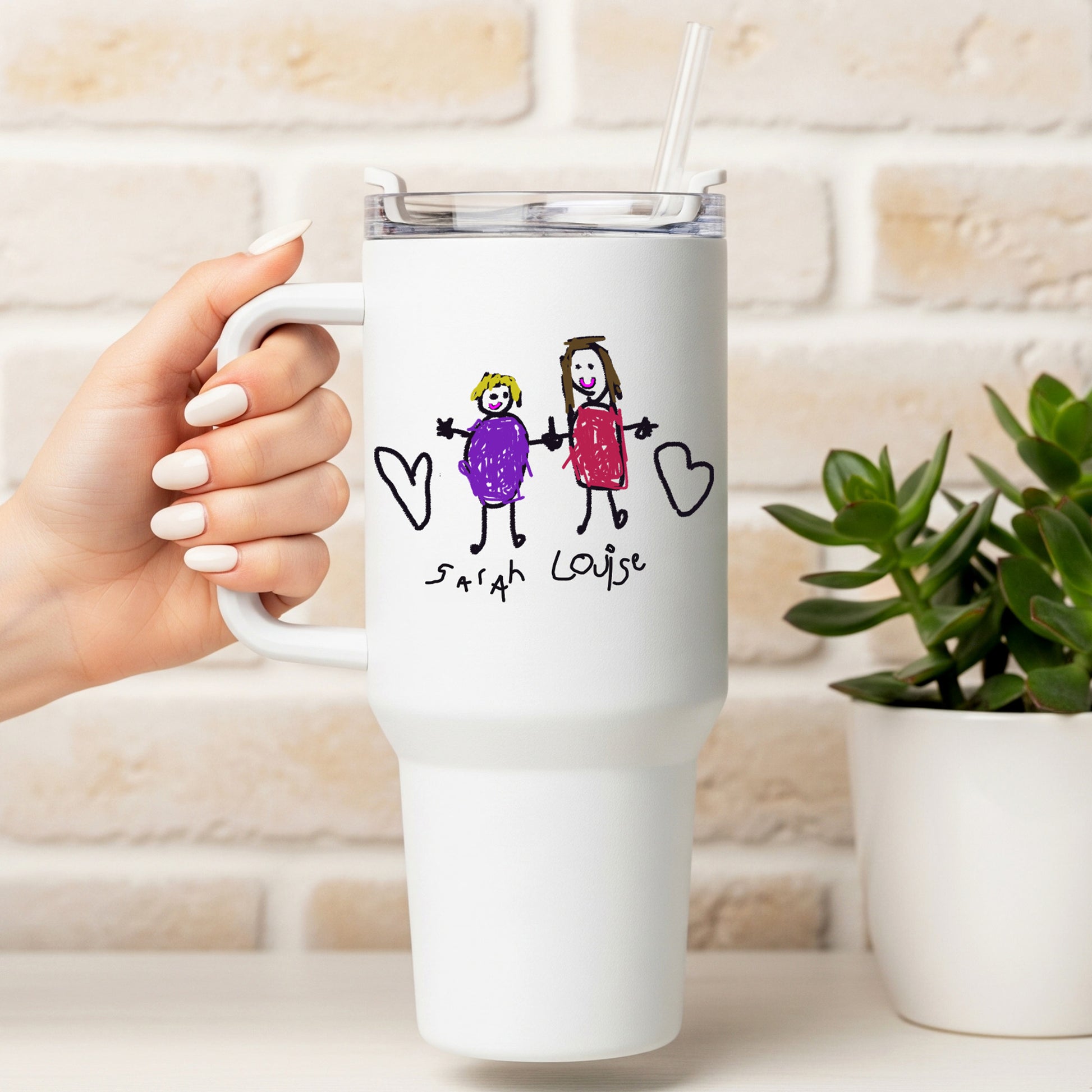 White travel mug with a hand-drawn design of two people holding hands and hearts, held by a hand against a light-colored brick wall. | Little Heirloom