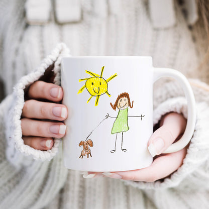 Person holding a mug with a child-like drawing of a sun, girl, and dog. | Little Heirloom