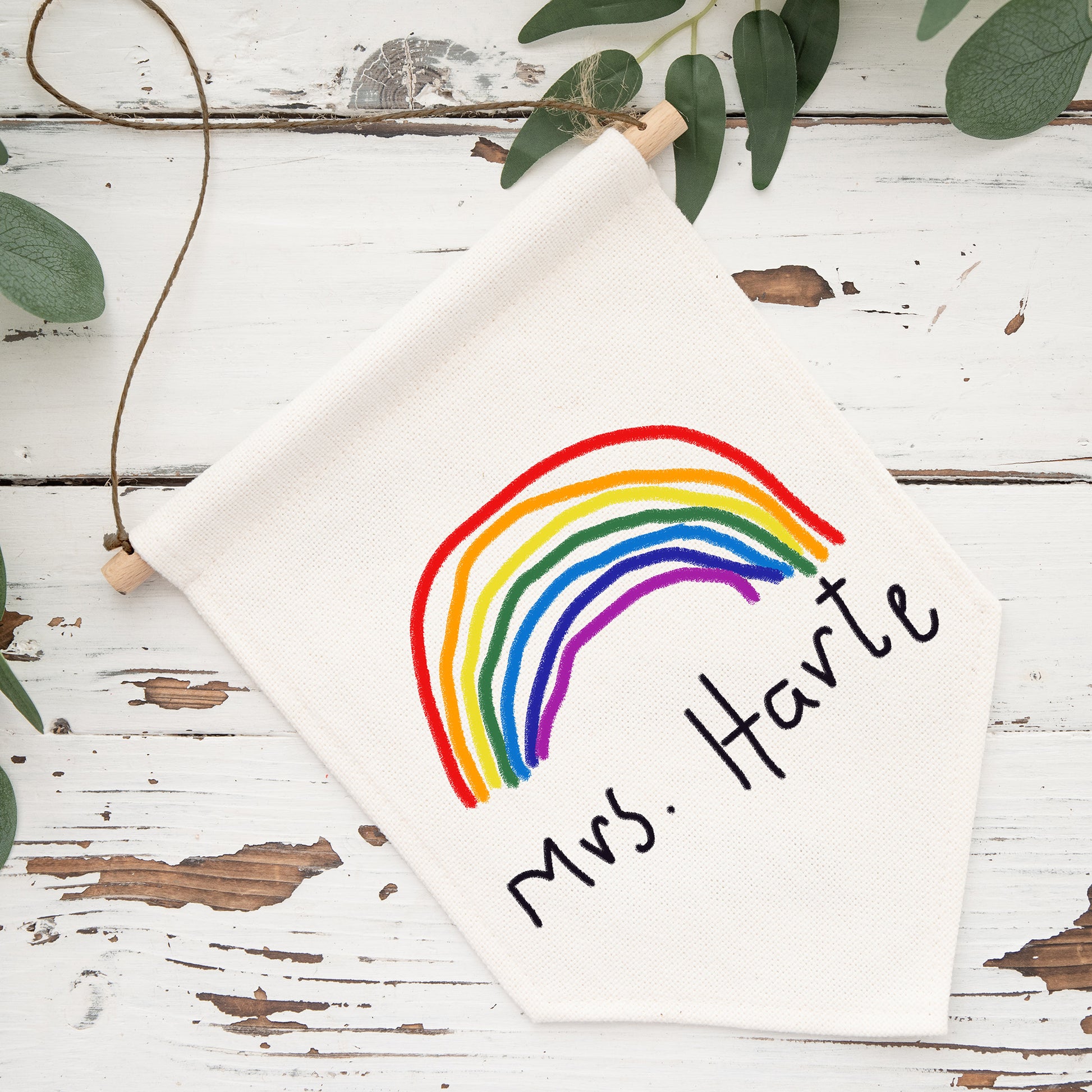 White hexagonal sign with rainbow and 'Mrs. Harte' text on a rustic wooden surface with greenery. | Little Heirloom