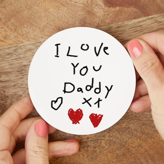 Round white coaster with 'I Love You Daddy' text held by hands on a wooden surface| Little Heirloom