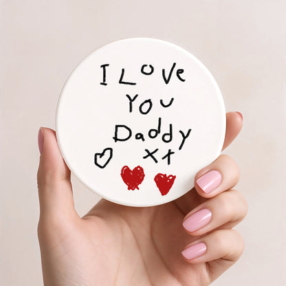 Hand holding a round white coaster with 'I Love You Daddy' text and heart symbols. | Little Heirloom