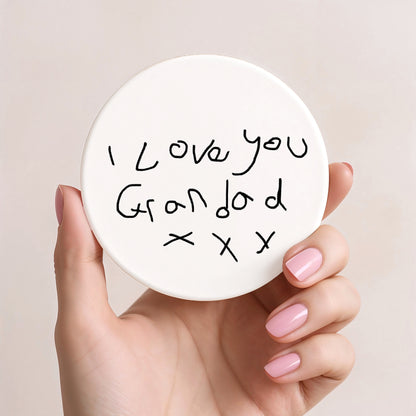 Hand holding a round white card with 'I love you Grandad x x x' text on a beige background| Little Heirloom