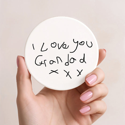 Hand holding a round white card with 'I love you Grandad x x x' text on a beige background| Little Heirloom