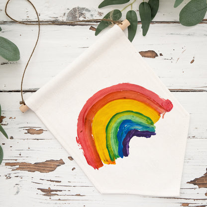 Children's drawing of a rainbow on a white sheet of paper with green leaves in the background. | Little Heirloom