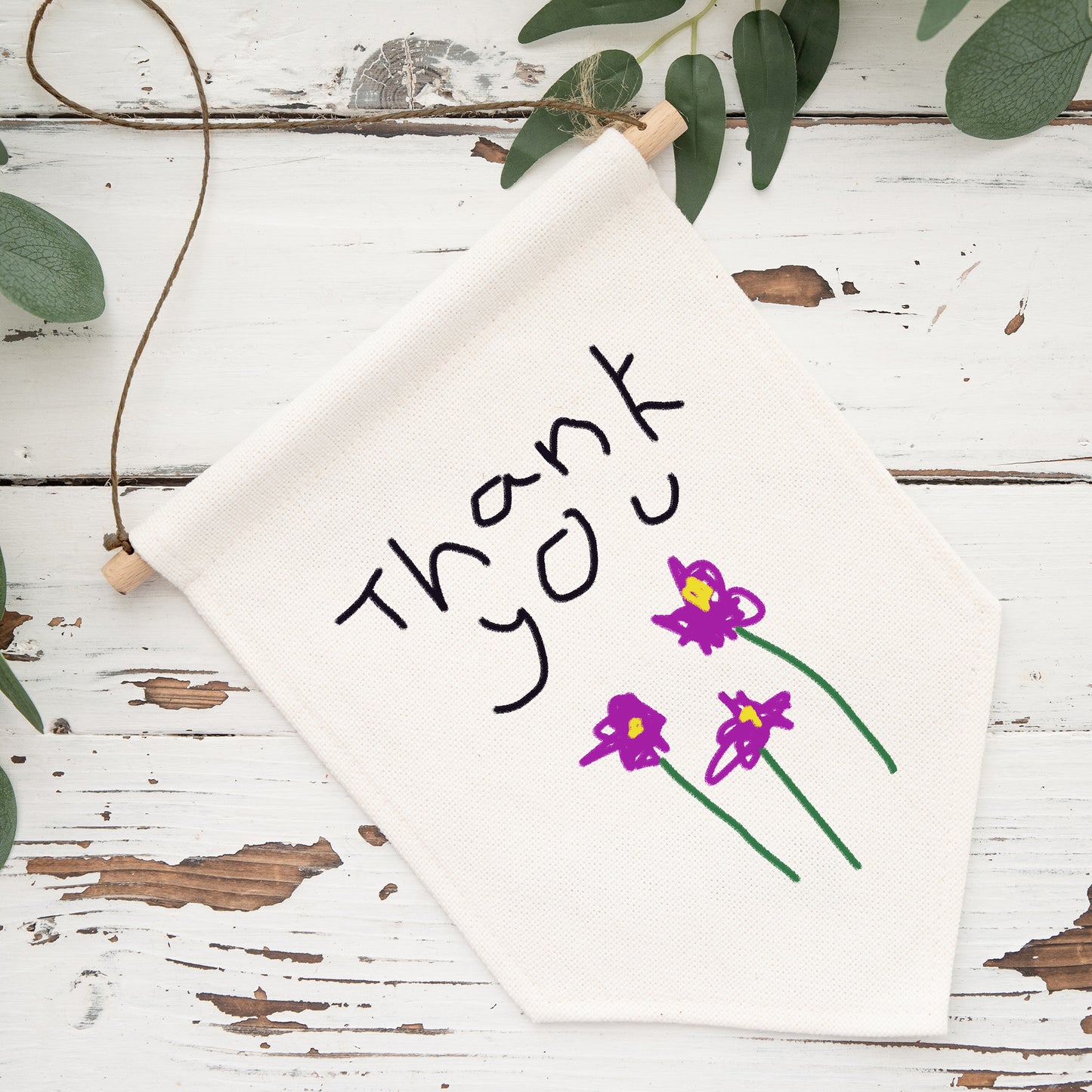 White napkin with 'Thank You' and purple flowers on a rustic wooden surface with green leaves. | Little Heirloom