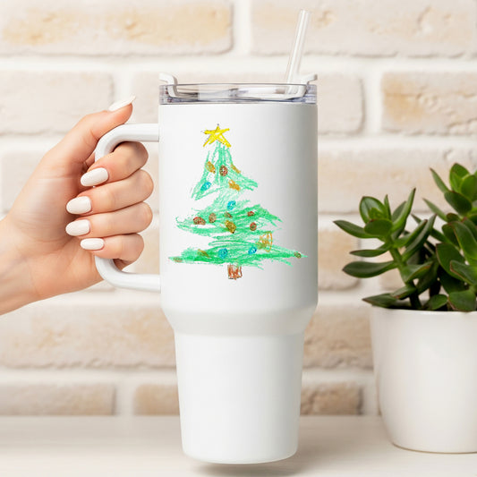 White tumbler with a Christmas tree design held by a hand, against a light brick wall.. | Little Heirloom