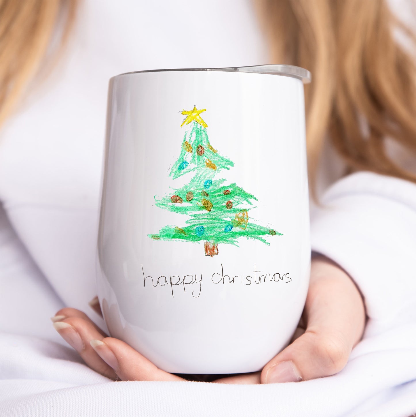 White tumbler with a Christmas tree design and 'happy Christmas' text held by a person. | Little Heirloom